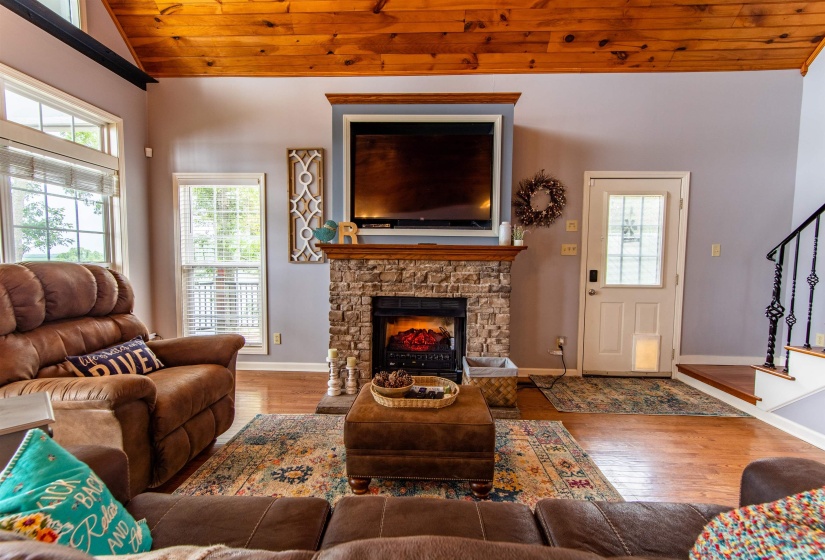 Living area featuring wood finished floors, wood ceiling, a stone fireplace, and stairs
