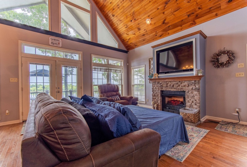 Living room featuring high vaulted ceiling, a fireplace, light wood-style flooring, french doors, and wood ceiling