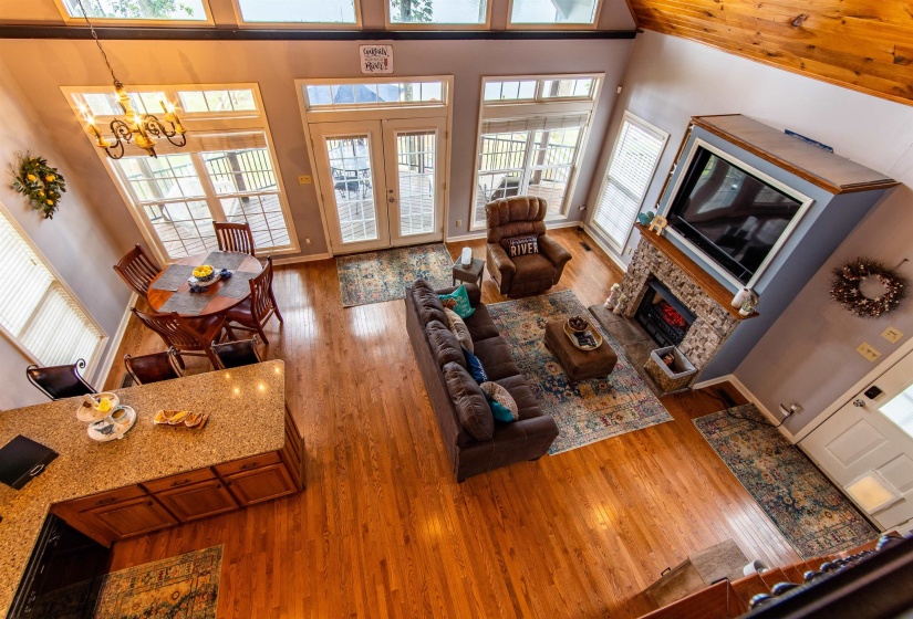 Living area featuring hardwood / wood-style flooring, a high ceiling, electric fireplace, french doors, and a chandelier