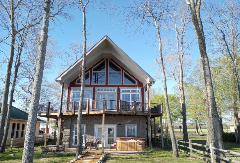 Rear view of property featuring a hot tub and a deck