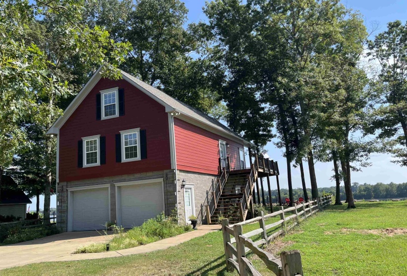 View of property exterior with stairs, driveway, a garage, stone and siding