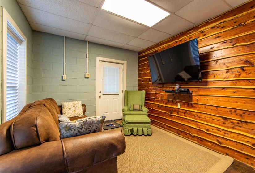 Garage floor living area with a paneled ceiling, concrete block wall, and wood walls