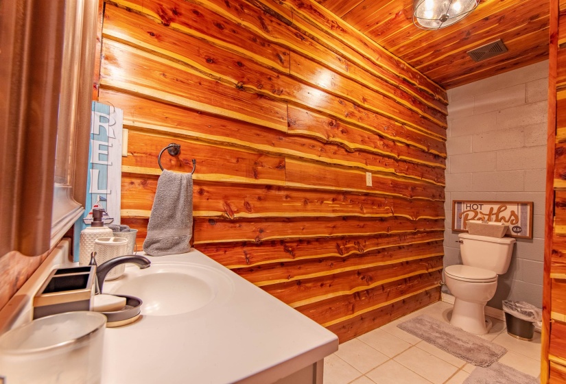 Garage bathroom featuring light tile patterned floors, vanity, wood ceiling, and concrete block wall