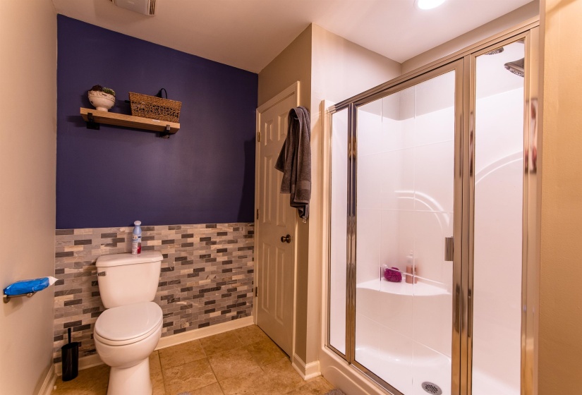 Bathroom with a stall shower, tile patterned floors, wainscoting, and tile walls
