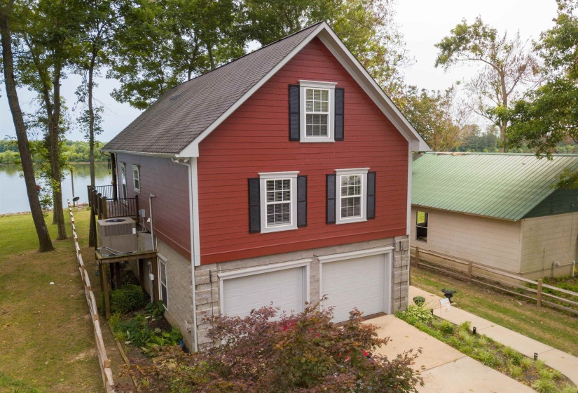 View of home's exterior with driveway, an attached garage, a shingled roof, stone and siding
