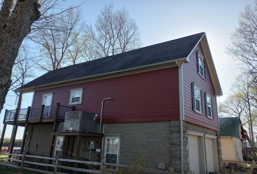Home featuring an attached garage, a deck, and a shingled roof