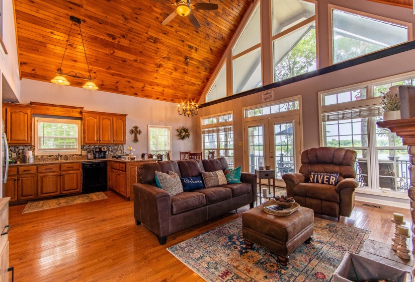 Living room featuring high vaulted ceiling, light wood finished floors, a chandelier, french doors, and ceiling fan