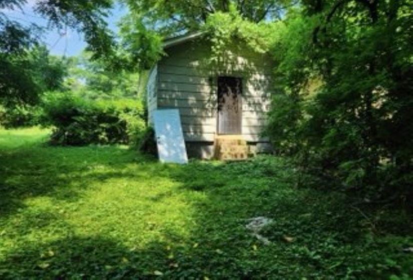 View of side of home featuring a storage unit and a lawn