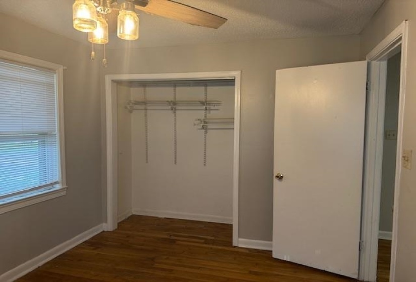 Unfurnished bedroom featuring wood finished floors, a closet, and a ceiling fan
