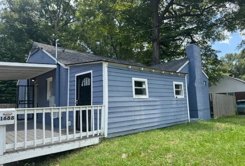 View of side of property featuring a chimney, a yard, and a shingled roof