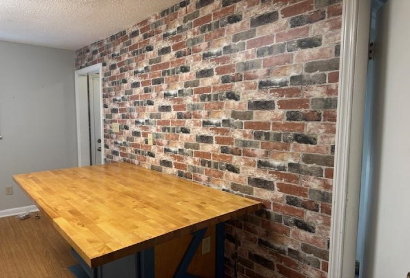 Dining space featuring brick wall, wood finished floors, and a textured ceiling