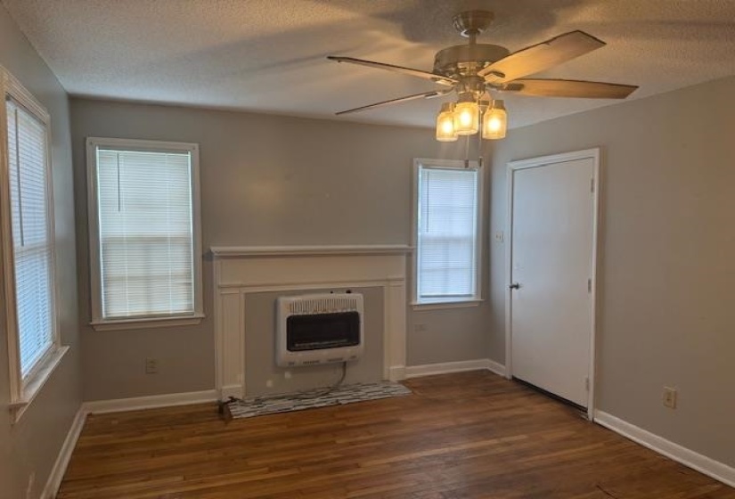 Unfurnished living room with heating unit, wood finished floors, healthy amount of natural light, and a textured ceiling