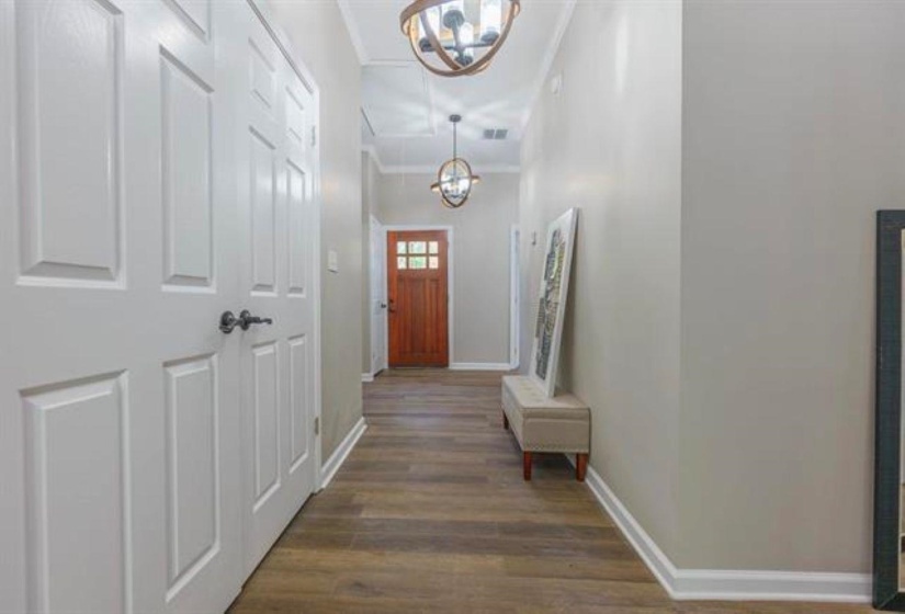 Doorway featuring a chandelier, wood finished floors, and ornamental molding
