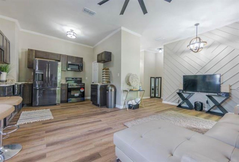 Living room with light wood-type flooring, ornamental molding, and ceiling fan