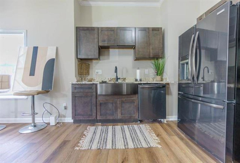 Kitchen with fridge with ice dispenser, crown molding, dark brown cabinetry, dishwasher, and light wood-type flooring