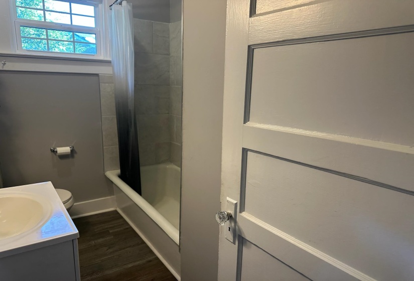 Bathroom featuring shower / tub combo, vanity, and dark wood-style floors