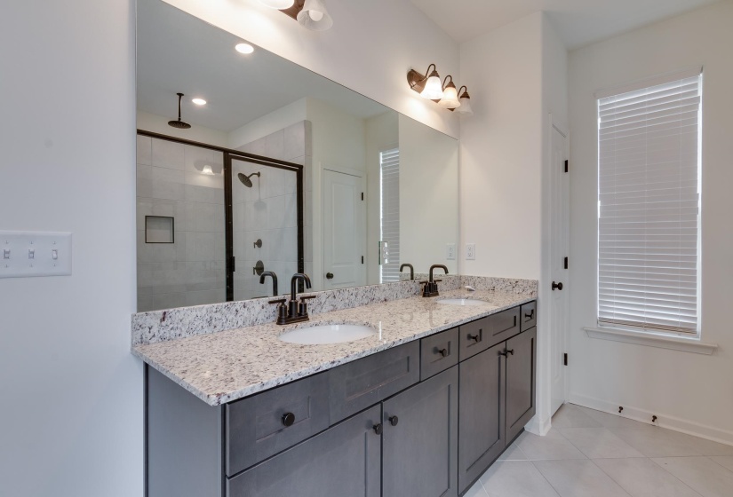Full bathroom featuring double vanity, a stall shower, and light tile patterned floors