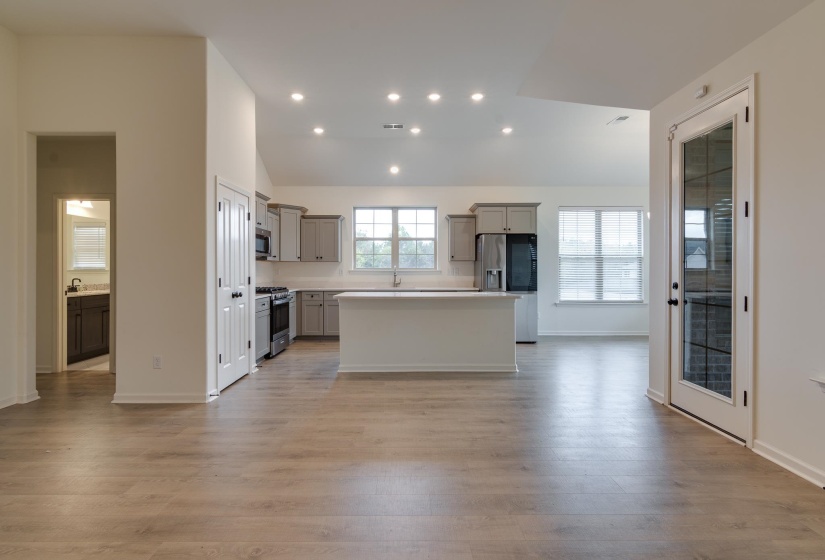 Kitchen with gray cabinets, a kitchen island, light countertops, recessed lighting, and lofted ceiling