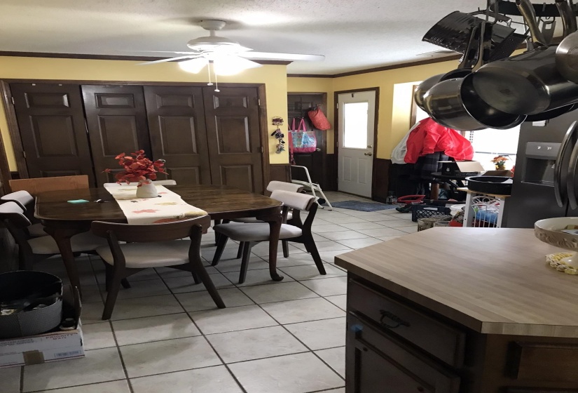 Dining space featuring crown molding, light tile patterned floors, a textured ceiling, and wainscoting