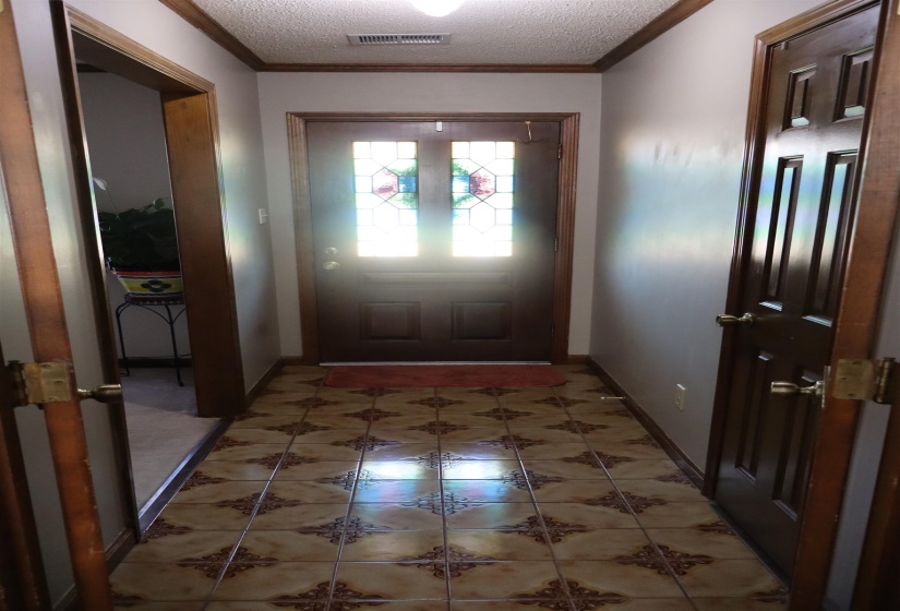Entryway featuring a textured ceiling, tile patterned flooring, and ornamental molding