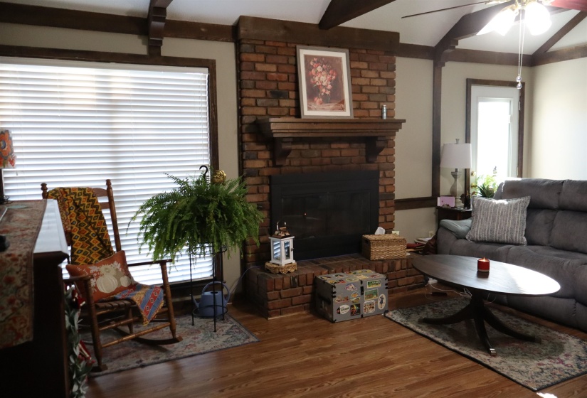 Living area with a ceiling fan, a fireplace, and wood finished floors