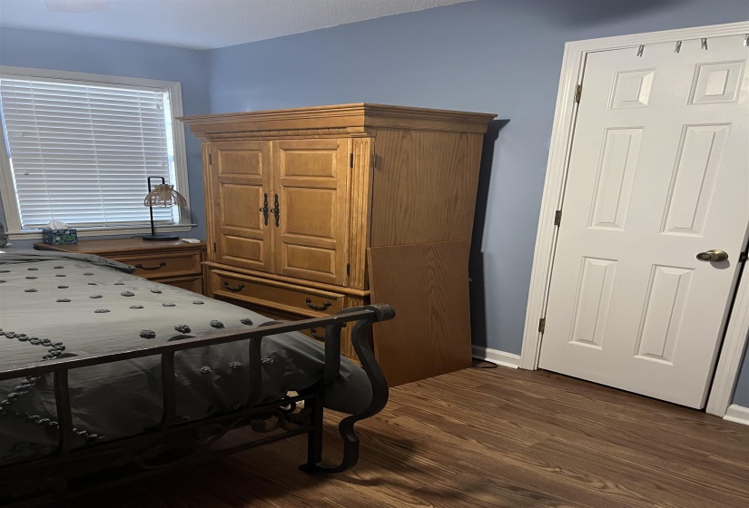 Bedroom with dark wood-type flooring and baseboards