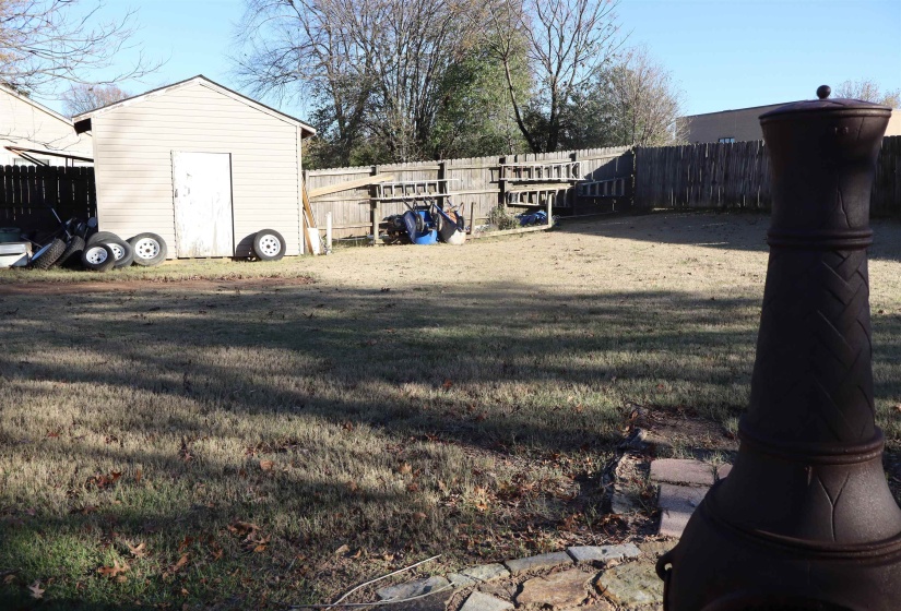 Fenced backyard featuring a shed