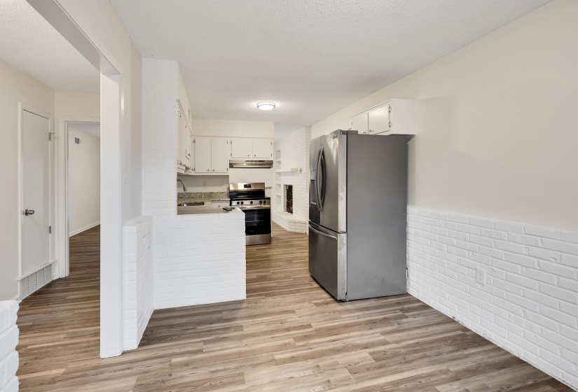Kitchen with stainless steel appliances, white cabinetry, light wood-type flooring, a wainscoted wall, and a peninsula