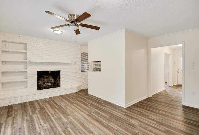Unfurnished living room with wood finished floors, a textured ceiling, ceiling fan, a fireplace, and ornamental molding