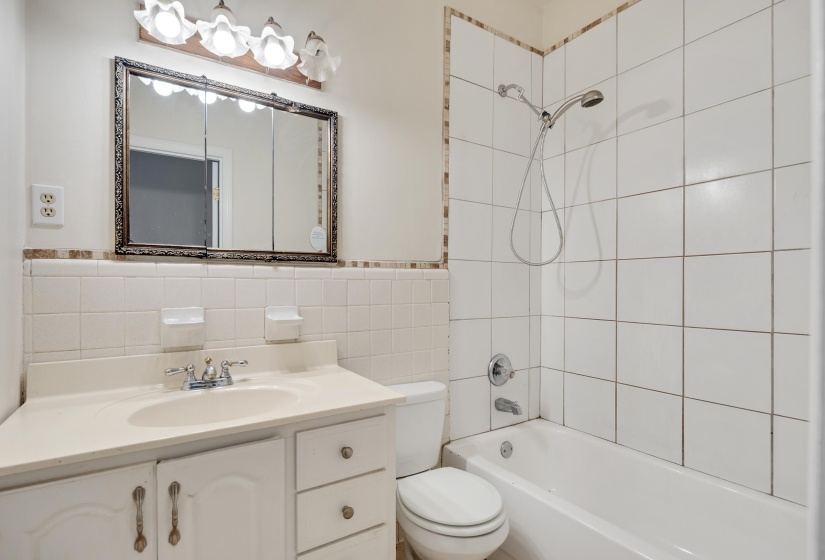 Bathroom with shower / tub combination, tile walls, and vanity