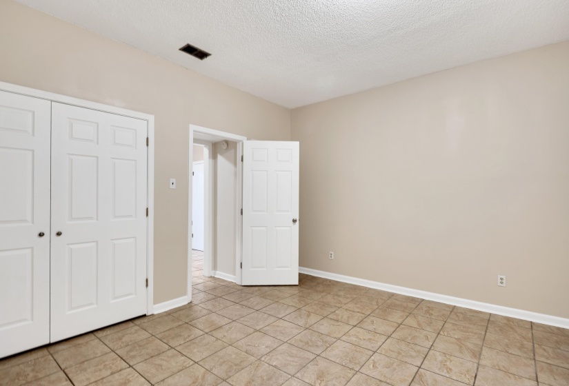 Unfurnished bedroom featuring a textured ceiling, a closet, and light tile patterned flooring