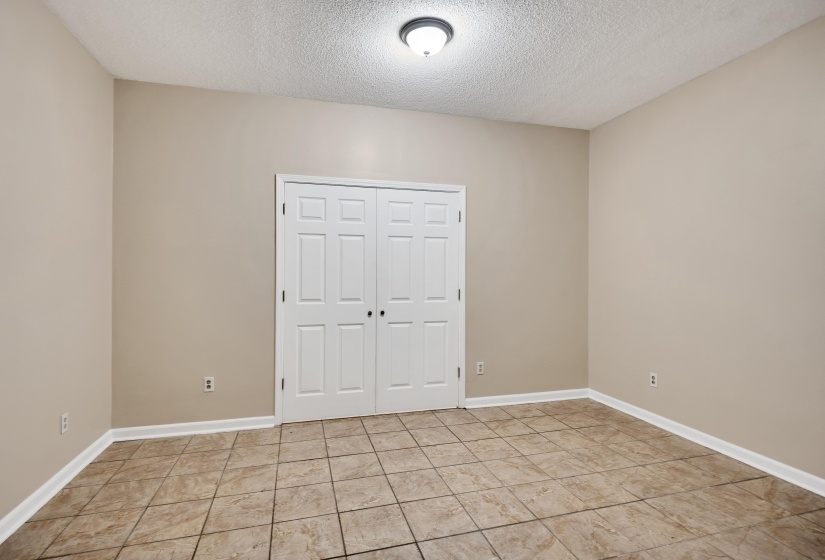 Unfurnished bedroom featuring a textured ceiling, a closet, and light tile patterned flooring