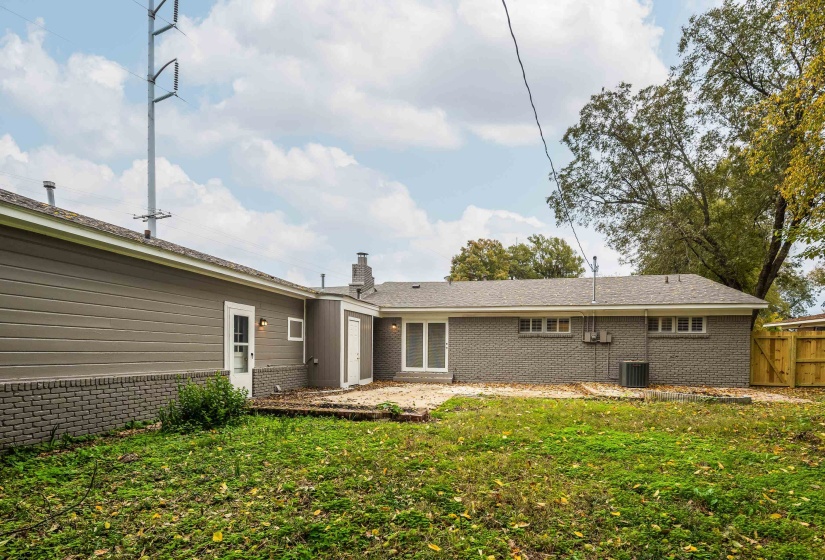 Back of house featuring brick siding, a chimney, and a patio area