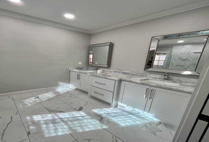 Bathroom featuring ornamental molding, double vanity, light marble finish flooring, and recessed lighting