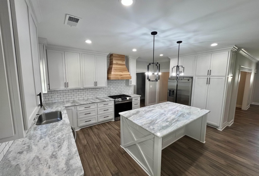 Kitchen featuring appliances with stainless steel finishes, pendant lighting, white cabinets, a kitchen island, and decorative backsplash