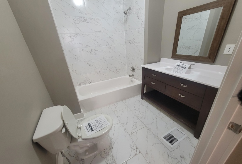 Full bath featuring light marble finish floors, vanity, and bathing tub / shower combination