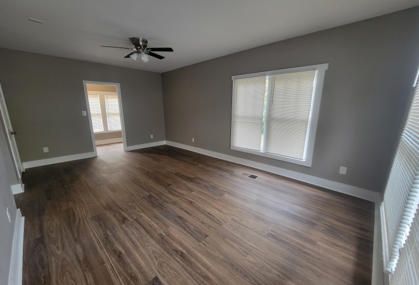 Spare room featuring dark wood-type flooring, plenty of natural light, and ceiling fan