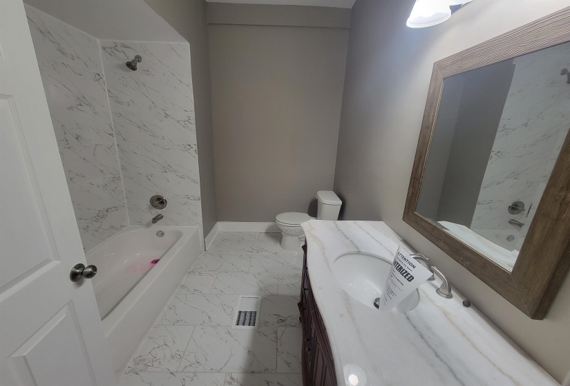 Bathroom featuring shower / bath combination, light marble finish floors, and vanity