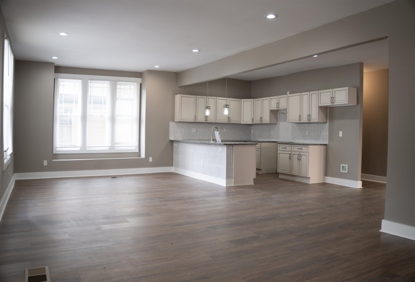 Kitchen with backsplash, a peninsula, dark wood-type flooring, recessed lighting, and open floor plan