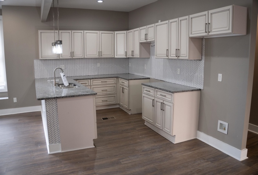 Kitchen with dark stone counters, a peninsula, tasteful backsplash, and pendant lighting