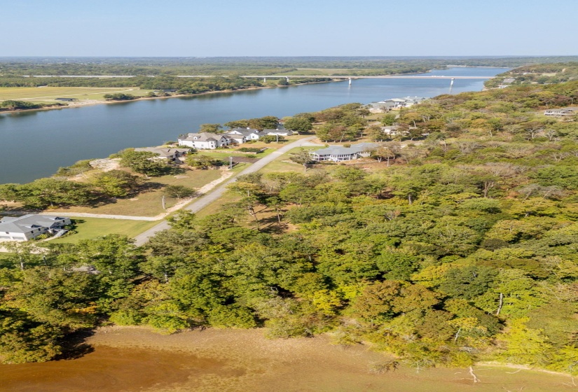 Drone / aerial view of a nearby body of water and a heavily wooded area