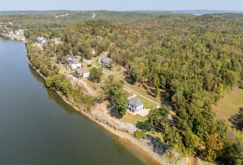 Aerial view of property and surrounding area with a large body of water and a heavily wooded area