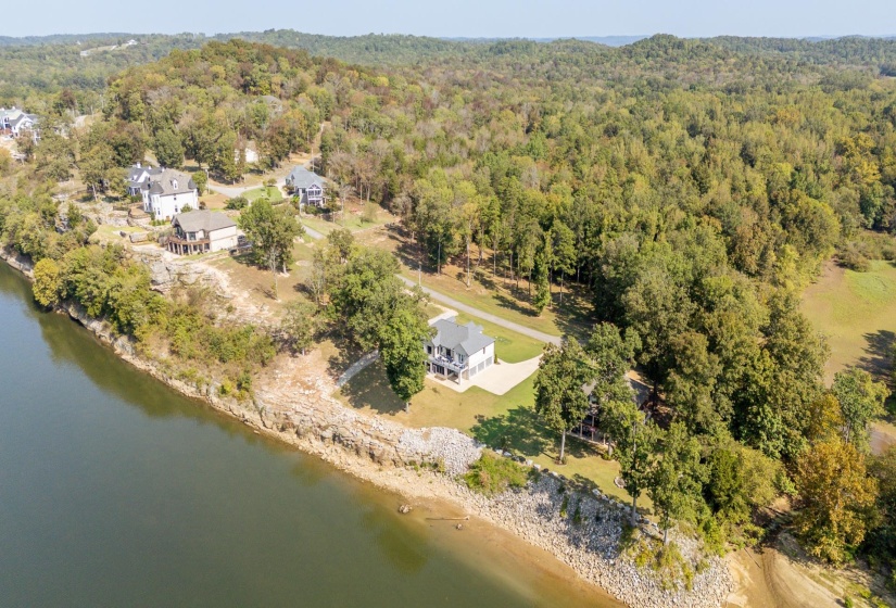 Aerial view of property and surrounding area featuring a nearby body of water and a forest