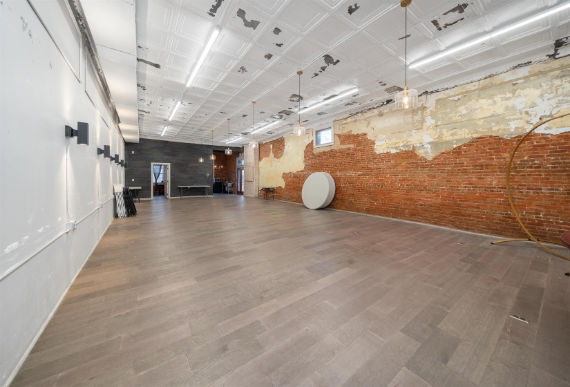 Empty room with brick wall, wood finished floors, and an ornate ceiling