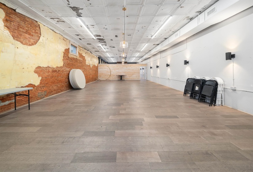 Miscellaneous room with brick wall, an ornate ceiling, and wood finished floors