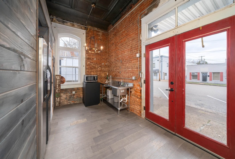 Doorway with wood finished floors, an ornate ceiling, and brick wall