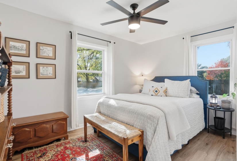 Bedroom with light wood-style floors, a ceiling fan, and multiple windows
