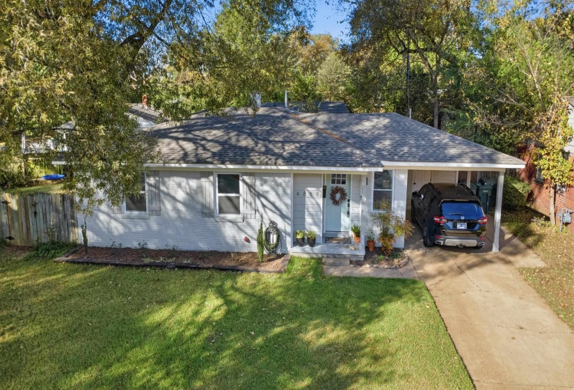 Ranch-style home featuring a shingled roof, a carport, driveway, and brick siding