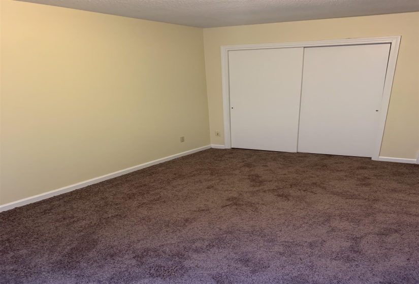 Unfurnished bedroom featuring dark colored carpet, a textured ceiling, and a closet