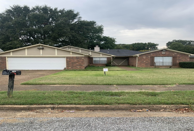 Ranch-style home featuring brick siding, a front lawn, a chimney, and driveway